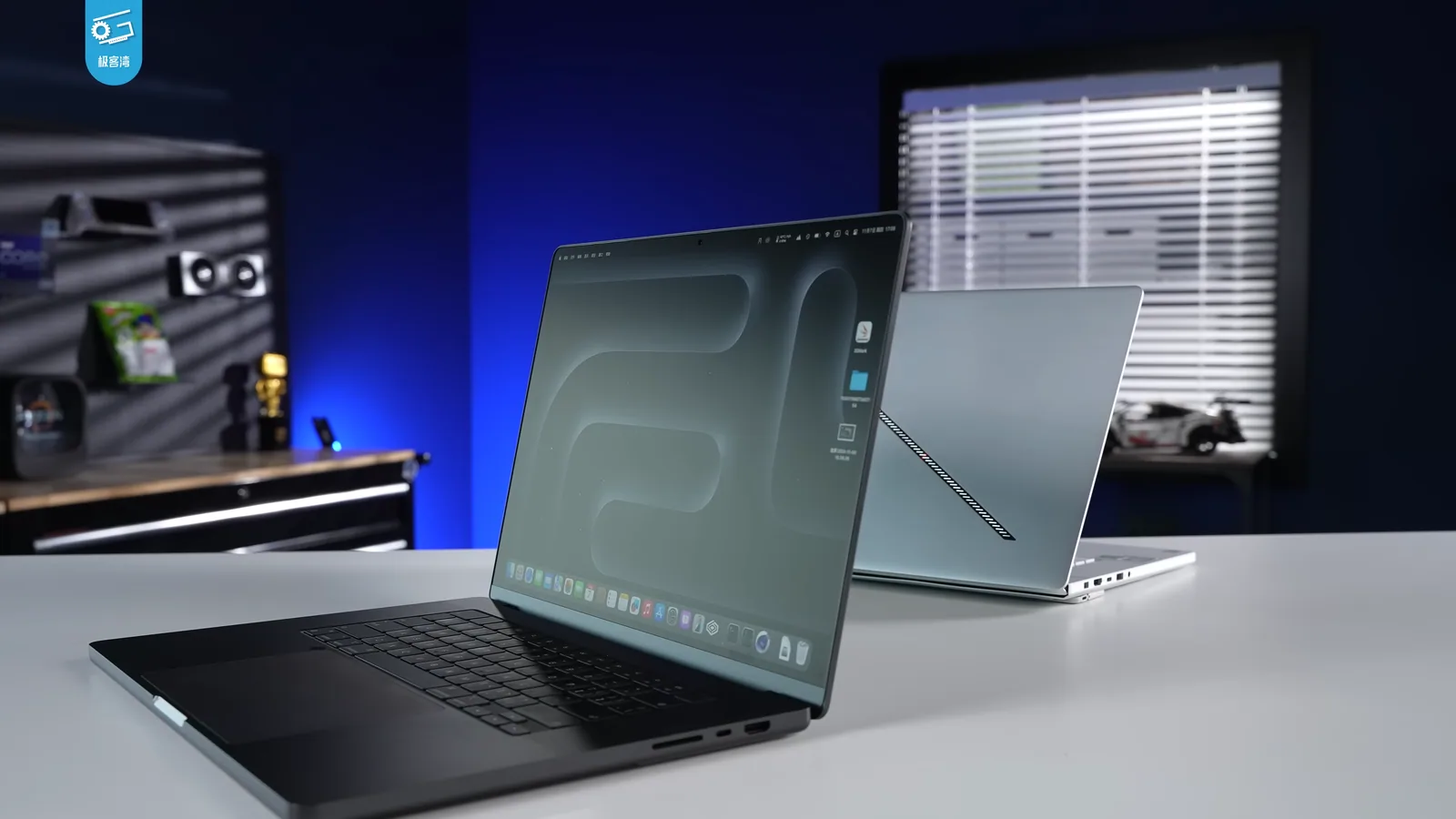 Deux MacBook Pro, un noir et un argent, posés sur un bureau dans une pièce éclairée en bleu